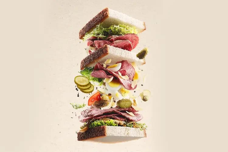 Sandwich Pastra-Club en éclaté — pastrami de la boucherie Dierendonck, salade, œuf dur et cornichons en suspension entre les tranches de pain